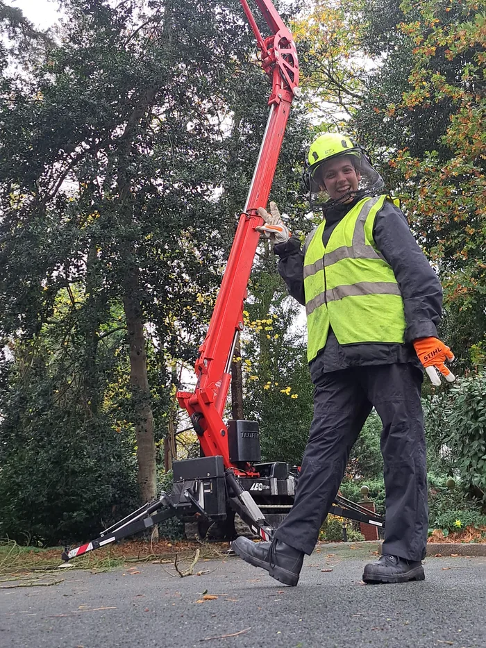 Kat in hi-vis and helmet beside the tracked spider lift on a job